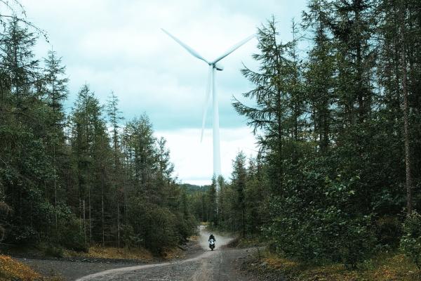 a biker in a forest with a wind turbine in the background 