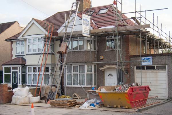 a house undergoing maintenance work with scaffolding and a skip on the driveway