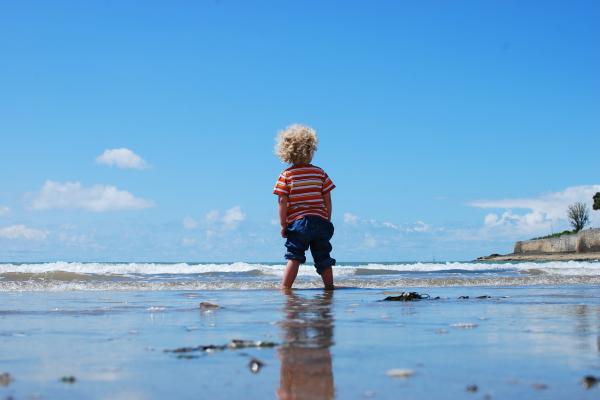 child looking out to sea on a beach